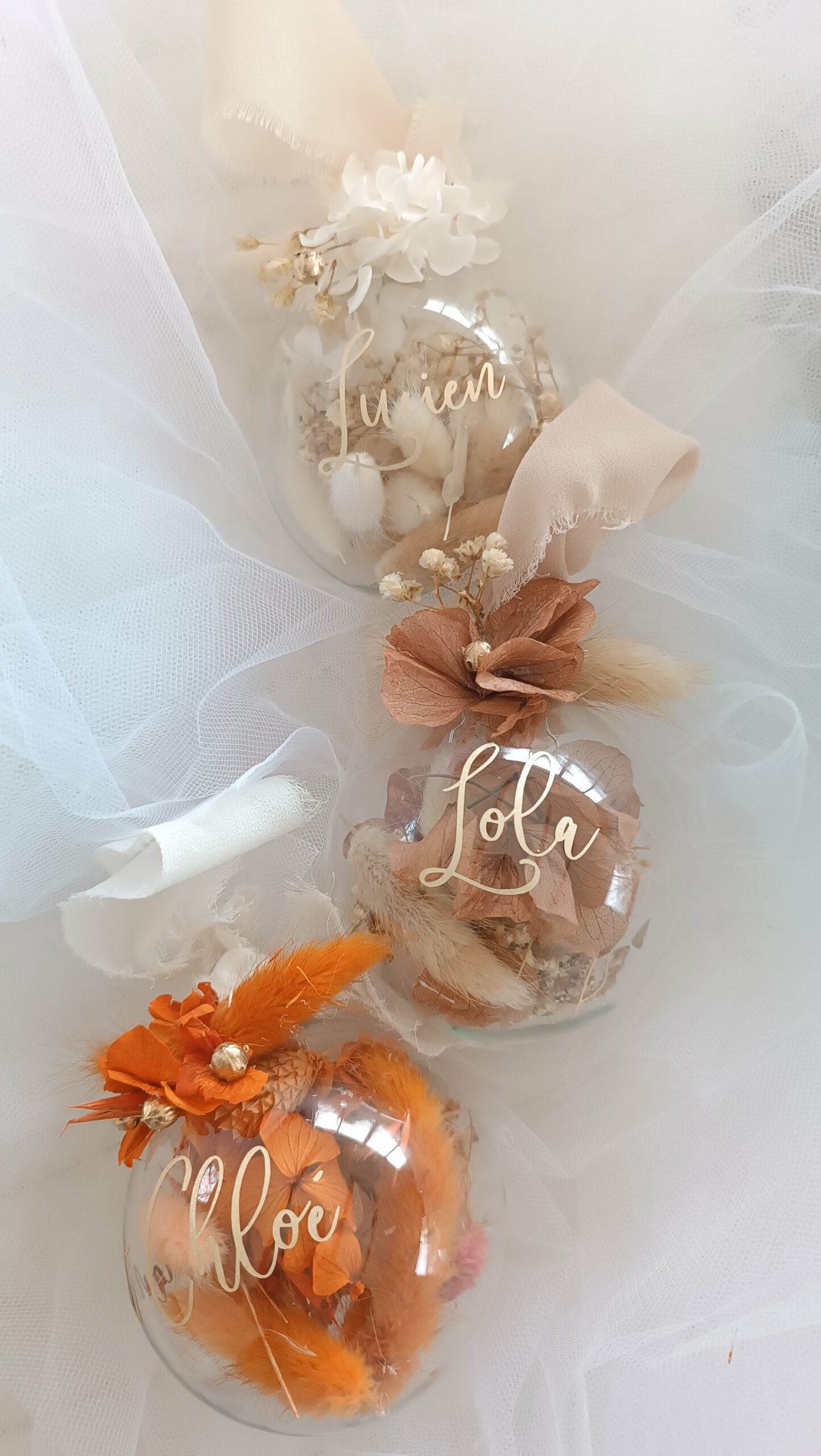 Boule de Noël en verre personnalisée avec prénom, remplie de fleurs séchées naturelles et décorée sur le dessus, idéale pour embellir le sapin et apporter une touche festive et élégante. Décoration de sapin de Noël originale, boule personnalisée en verre avec prénom gravé, contenant des fleurs séchées colorées, parfaite pour une ambiance chaleureuse et authentique. Boule de Noël artisanale en verre, personnalisable avec prénom, garnie de fleurs séchées à l’intérieur, un ornement raffiné pour sapin de Noël et décoration festive de fin d’année. Boue de noël pour mon 1er noël, joyeux noël , belles fêtes de fin d'année, cadeau à personnaliser, idée cadeau fait main à personnaliser avec prénom ou meesage. Ornement de Noël en verre transparent, boule personnalisée avec prénom et fleurs séchées, une décoration unique et naturelle pour sapin de Noël traditionnel ou moderne. Merry Christmas