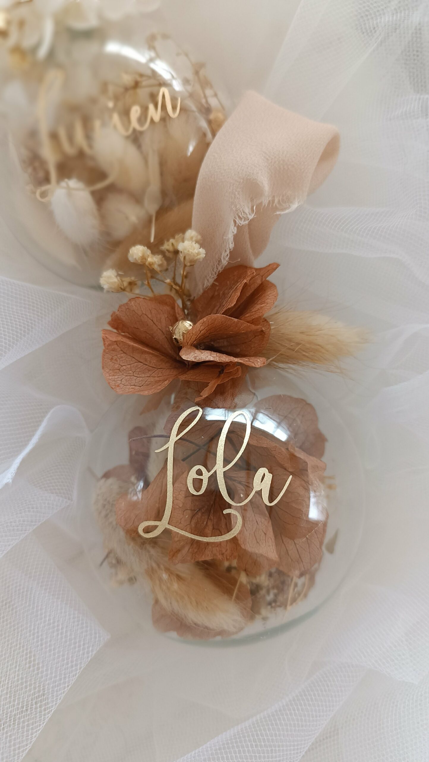 Boule de Noël en verre personnalisée avec prénom, remplie de fleurs séchées naturelles et décorée sur le dessus, idéale pour embellir le sapin et apporter une touche festive et élégante. Décoration de sapin de Noël originale, boule personnalisée en verre avec prénom gravé, contenant des fleurs séchées colorées, parfaite pour une ambiance chaleureuse et authentique. Boule de Noël artisanale en verre, personnalisable avec prénom, garnie de fleurs séchées à l’intérieur, un ornement raffiné pour sapin de Noël et décoration festive de fin d’année. Boue de noël pour mon 1er noël, joyeux noël , belles fêtes de fin d'année, cadeau à personnaliser, idée cadeau fait main à personnaliser avec prénom ou meesage. Ornement de Noël en verre transparent, boule personnalisée avec prénom et fleurs séchées, une décoration unique et naturelle pour sapin de Noël traditionnel ou moderne. Merry Christmas