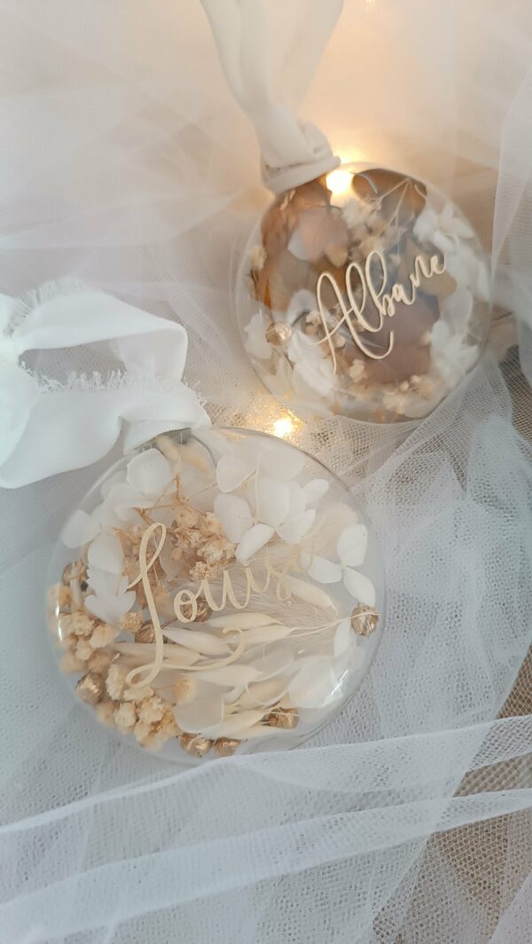 Boule de Noël en verre personnalisée avec prénom, remplie de fleurs séchées naturelles et décorée sur le dessus, idéale pour embellir le sapin et apporter une touche festive et élégante. Décoration de sapin de Noël originale, boule personnalisée en verre avec prénom gravé, contenant des fleurs séchées colorées, parfaite pour une ambiance chaleureuse et authentique. Boule de Noël artisanale en verre, personnalisable avec prénom, garnie de fleurs séchées à l’intérieur, un ornement raffiné pour sapin de Noël et décoration festive de fin d’année. Boue de noël pour mon 1er noël, joyeux noël , belles fêtes de fin d'année, cadeau à personnaliser, idée cadeau fait main à personnaliser avec prénom ou meesage. Ornement de Noël en verre transparent, boule personnalisée avec prénom et fleurs séchées, une décoration unique et naturelle pour sapin de Noël traditionnel ou moderne. Merry Christmas