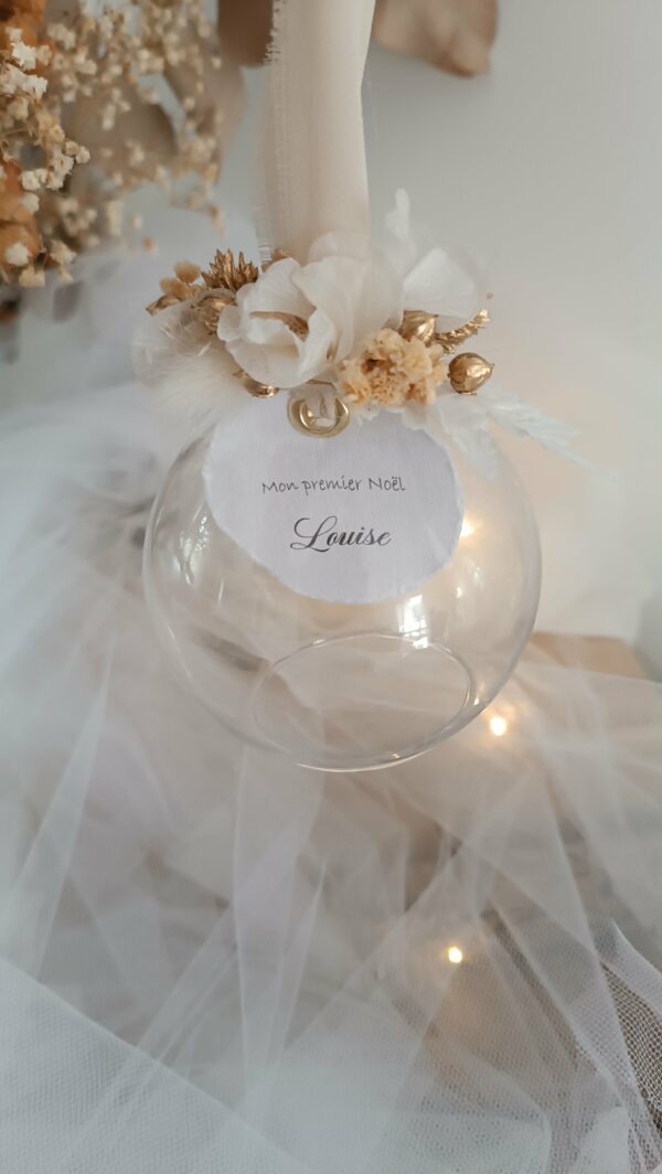 Boule de Noël en verre personnalisée avec prénom, remplie de fleurs séchées naturelles et décorée sur le dessus, idéale pour embellir le sapin et apporter une touche festive et élégante. Décoration de sapin de Noël originale, boule personnalisée en verre avec prénom gravé, contenant des fleurs séchées colorées, parfaite pour une ambiance chaleureuse et authentique. Boule de Noël artisanale en verre, personnalisable avec prénom, garnie de fleurs séchées à l’intérieur, un ornement raffiné pour sapin de Noël et décoration festive de fin d’année. Boue de noël pour mon 1er noël, joyeux noël , belles fêtes de fin d'année, cadeau à personnaliser, idée cadeau fait main à personnaliser avec prénom ou meesage. Ornement de Noël en verre transparent, boule personnalisée avec prénom et fleurs séchées, une décoration unique et naturelle pour sapin de Noël traditionnel ou moderne. Merry Christmas