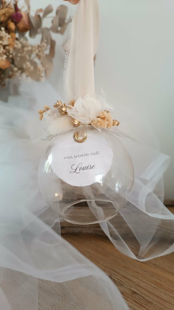 Boule de Noël en verre personnalisée avec prénom, remplie de fleurs séchées naturelles et décorée sur le dessus, idéale pour embellir le sapin et apporter une touche festive et élégante. Décoration de sapin de Noël originale, boule personnalisée en verre avec prénom gravé, contenant des fleurs séchées colorées, parfaite pour une ambiance chaleureuse et authentique. Boule de Noël artisanale en verre, personnalisable avec prénom, garnie de fleurs séchées à l’intérieur, un ornement raffiné pour sapin de Noël et décoration festive de fin d’année. Boue de noël pour mon 1er noël, joyeux noël , belles fêtes de fin d'année, cadeau à personnaliser, idée cadeau fait main à personnaliser avec prénom ou meesage. Ornement de Noël en verre transparent, boule personnalisée avec prénom et fleurs séchées, une décoration unique et naturelle pour sapin de Noël traditionnel ou moderne. Merry Christmas