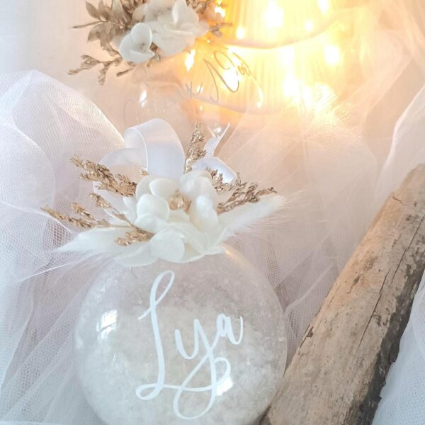 Boule de Noël en verre personnalisée avec prénom, remplie de fleurs séchées naturelles et décorée sur le dessus, idéale pour embellir le sapin et apporter une touche festive et élégante. Décoration de sapin de Noël originale, boule personnalisée en verre avec prénom gravé, contenant des fleurs séchées colorées, parfaite pour une ambiance chaleureuse et authentique. Boule de Noël artisanale en verre, personnalisable avec prénom, garnie de fleurs séchées à l’intérieur, un ornement raffiné pour sapin de Noël et décoration festive de fin d’année. Boue de noël pour mon 1er noël, joyeux noël , belles fêtes de fin d'année, cadeau à personnaliser, idée cadeau fait main à personnaliser avec prénom ou meesage. Ornement de Noël en verre transparent, boule personnalisée avec prénom et fleurs séchées, une décoration unique et naturelle pour sapin de Noël traditionnel ou moderne. Merry Christmas