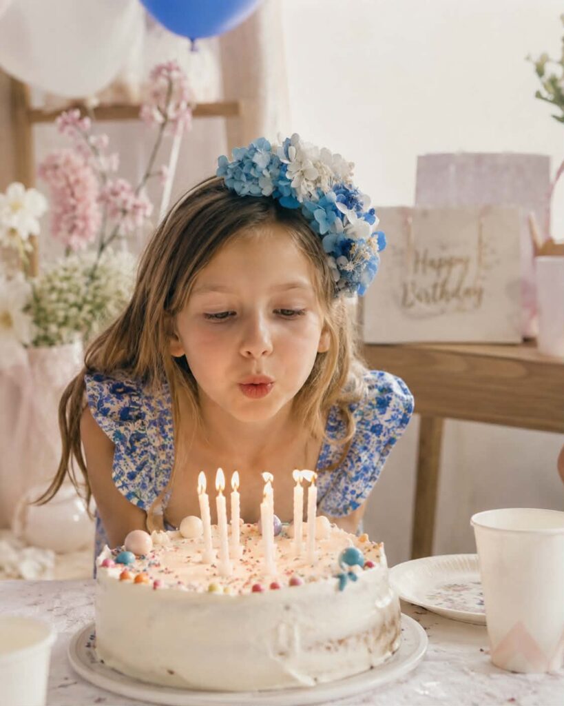 petite fille avec serre tête en fleurs séchées qui souffle ces bougies . ideal cadeau cheveux petite fille